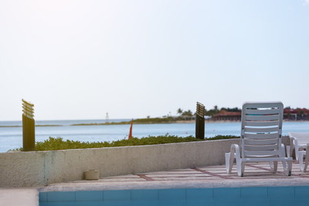 Lounge sunbeds near swimming pool at poolside, outdoor near caribbean sea. ocean viewの写真素材