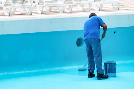 Unrecognizable worker repainting swimming pool in blue colour. Reconstruction processの写真素材