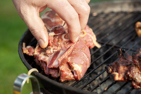 Cooking different meats on barbecue. Grilled and roasted lamb steaks on bbq. Take one piece. outdoorsの写真素材