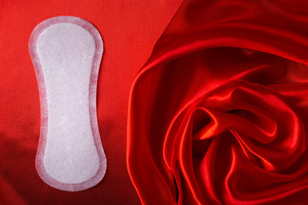 Female intimate care concept. Daily panty for hygiene on satin elegant material, drapery rose flowerの写真素材