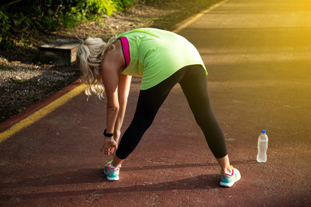 Fitness woman stretching her muscles before training, ready for jogging in summer park. Healthy lifestyle and sport conceptの写真素材