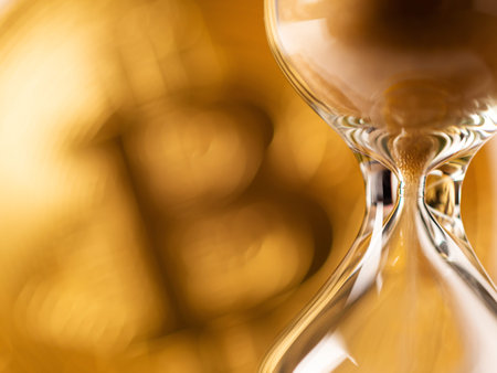 Sandglass closeup on golden background with bitcoin coin. Time is running. Hourglass with falling grainの写真素材