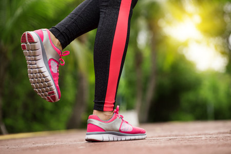 Fitness woman training and jogging in summer park, close up on running shoes in sunlight. Healthy lifestyle and sport conceptの写真素材