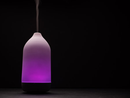 Purple light diffuser diffusing steam on black background. close upの写真素材