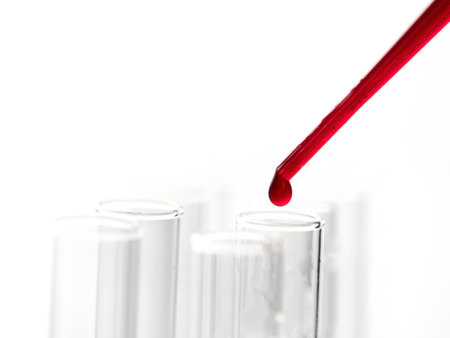 Pipette drip red liquid drops into laboratory test glass tubes, nobody. close upの写真素材