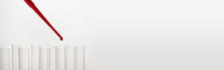 Pipette drip red liquid drops into laboratory test glass tubes, nobody. close upの写真素材