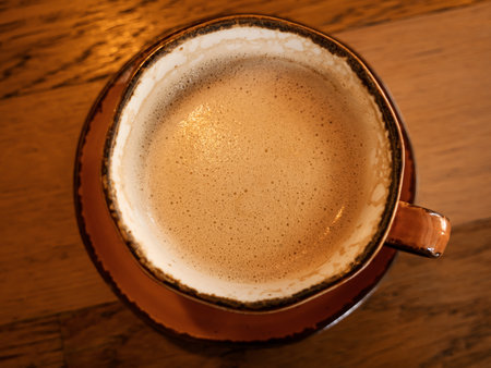 Cup of coffee on table in cafe. Mixing cappuccino with spoon. Closeupの写真素材