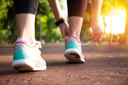 Runner woman tying up laces of shoes, getting ready to run for cardio and weight loss, no faceの写真素材