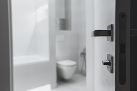 Open door to white monochrome bathroom with toilet in blurred background. Minimalism concept