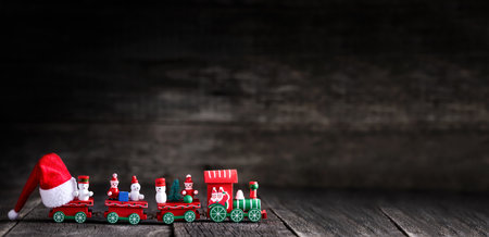Toy of christmas train with Santa Claus Hat on wooden rustic background. New year celebration. Winter holidays. Long bannerの写真素材