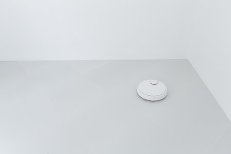 Vacuum cleaner cleaning white glass ceramic tile floor in empty roomの写真素材