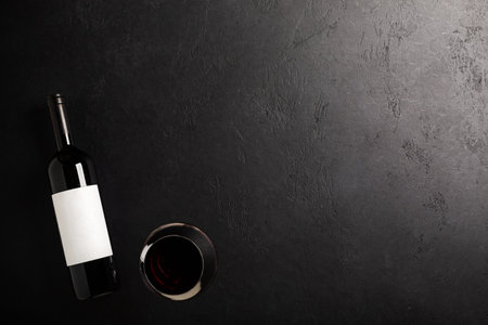 Glass and bottle with red wine on black background. Flat layの写真素材