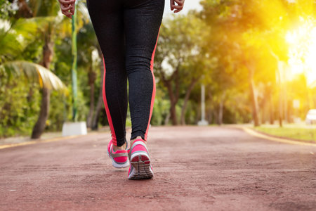 Woman running, training and jogging in summer park, closeup on running shoes