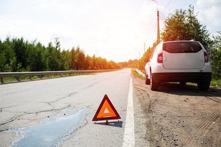 Car and red triangle emergency stop sign on asphalt road. Closeup. Nobodyの写真素材