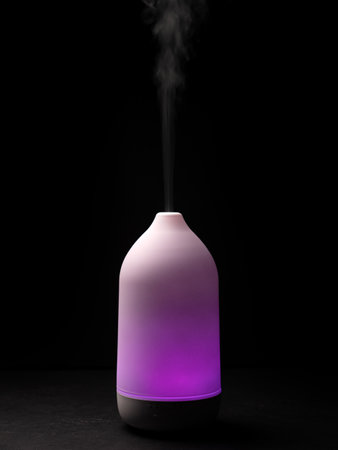 Diffuser with purple light diffusing steam on black background, closeupの写真素材