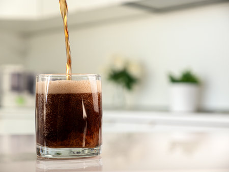 Pouring fizzing beverage in glass at the kitchen, closeupの写真素材