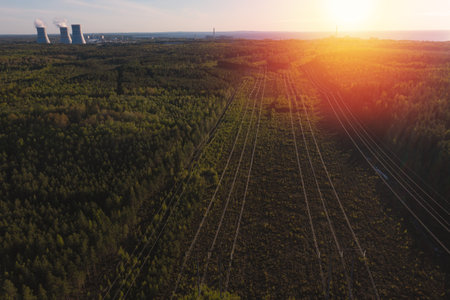 Smoking cooling towers at nuclear power plant and powerlines in forest. Sunset time. Aerial view from droneの写真素材
