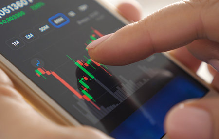 Online trading. Investor checking rates and graphs of stocks on smartphone. Closeupの写真素材