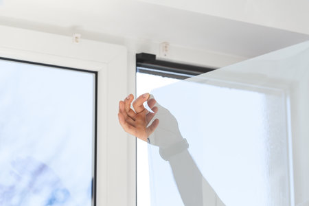 Professional worker tinting window with foil indoors, closeupの写真素材