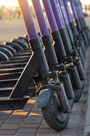 A lot of electric scooters in row parked on street for rent, closeup, selective focus, shallow depthの写真素材