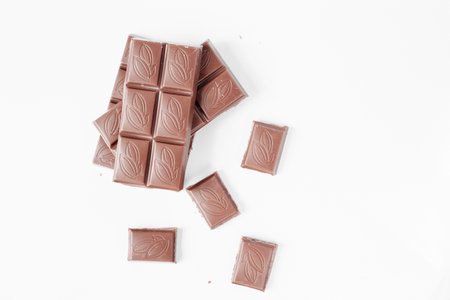 Milk chocolate pieces isolated on white background from top view, close up a chocolate bar isolated...