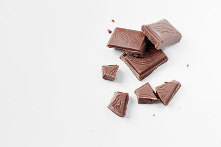 Milk chocolate pieces isolated on white background from top view, close up a chocolate bar isolated...
