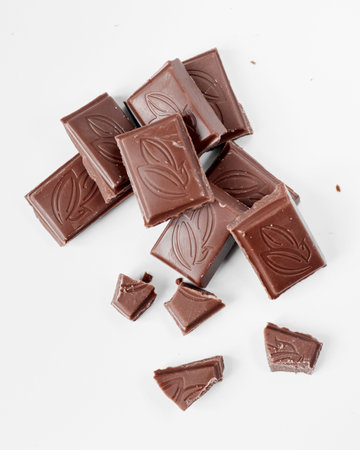 Milk chocolate pieces isolated on white background from top view, close up a chocolate bar isolated...