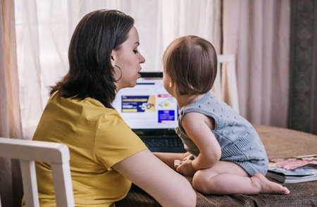Happy young mother and her daughter using a laptopのeditorial素材