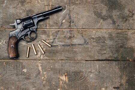Nagant revolver with cartridges on an old wooden surface in retro style. View from above. Place for...