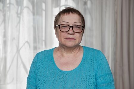 An elderly woman with glasses looks into the cameraの写真素材