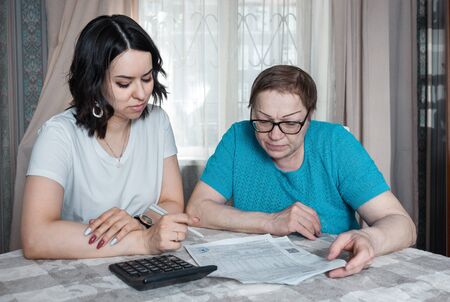 A young woman and an old lady are checking bills for paymentの写真素材