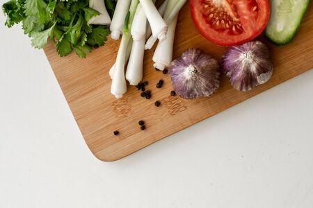 Fresh green onion, tomato and cucumber cut into slices, garlic on a wooden board. View from above. The concept of vegetarianism, healthy eatingの写真素材