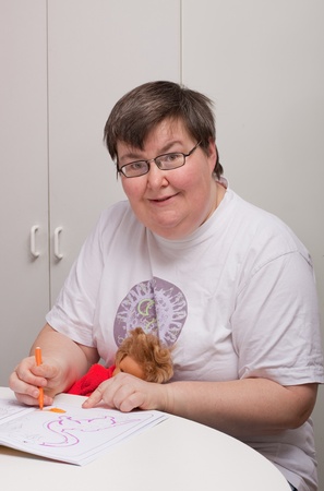 a sitting mentally disabled woman is painting a pictureの写真素材