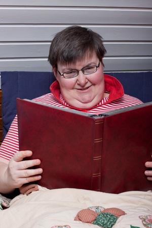 a sitting mentaly disabled woman reads and smilesの写真素材