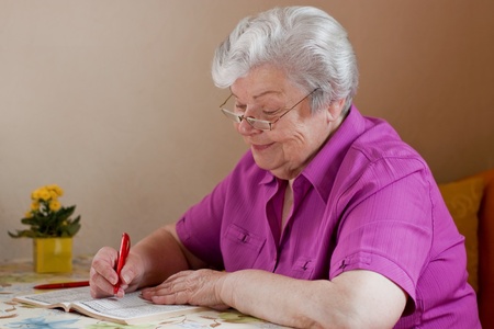 pensioner puzzles and smiles with reading glassesの写真素材
