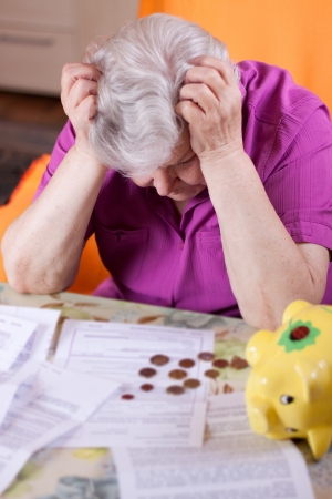 Elderly woman sits in front of papers and desperateの写真素材