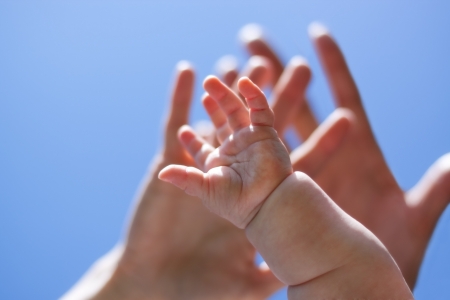 three hands from adults and baby stretch to the skyの写真素材