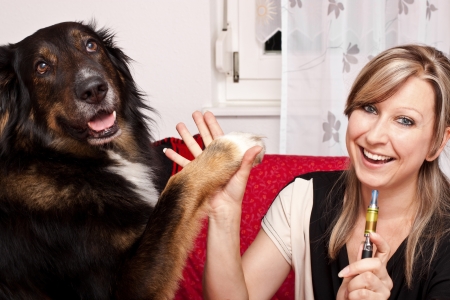 Blonde woman give dog high Five and evaporated electric cigaretteの写真素材