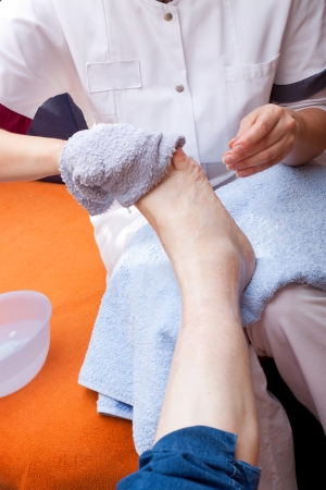 Geriatric nurse washes the foot of a patientの写真素材