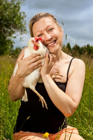 pretty blonde woman hugs an white chickenの写真素材