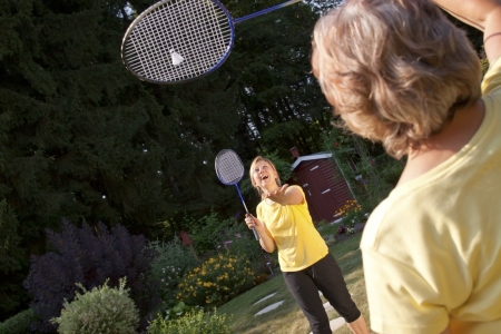 Two women playing badminton in the gardenの写真素材