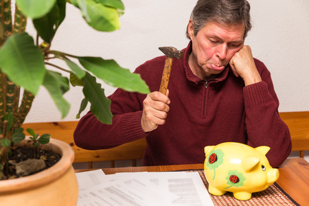 senior adult try to smash piggy bankの写真素材