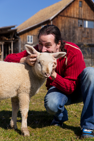 Man and lamb in front of a farmの写真素材