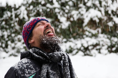 a man with outstreched tongue is catching snowflakesの写真素材