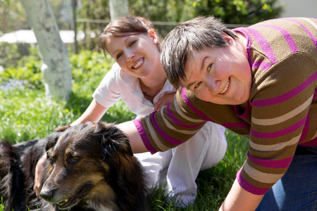 two women and a half breed dog on a fieldの写真素材