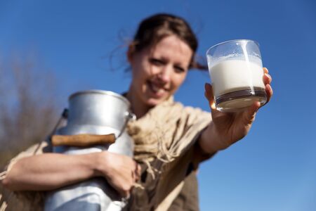 pretty peasant woman presents fresh milk from the cow