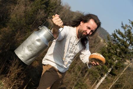 a long-haired grower offering a milk churn and breadの写真素材