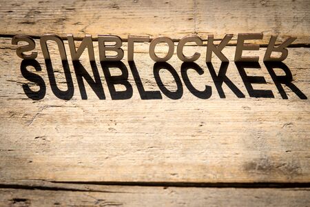 wooden letters on old aged wooden table build the shadow word sunblocker, vintage styleの写真素材
