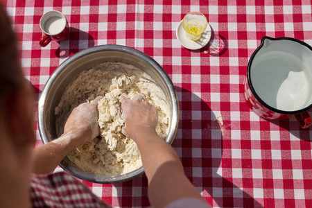 woman is kneading dough, red white tablecloth