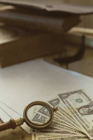 Mortar and books with magnifying glass, many dollars at the edgeの写真素材